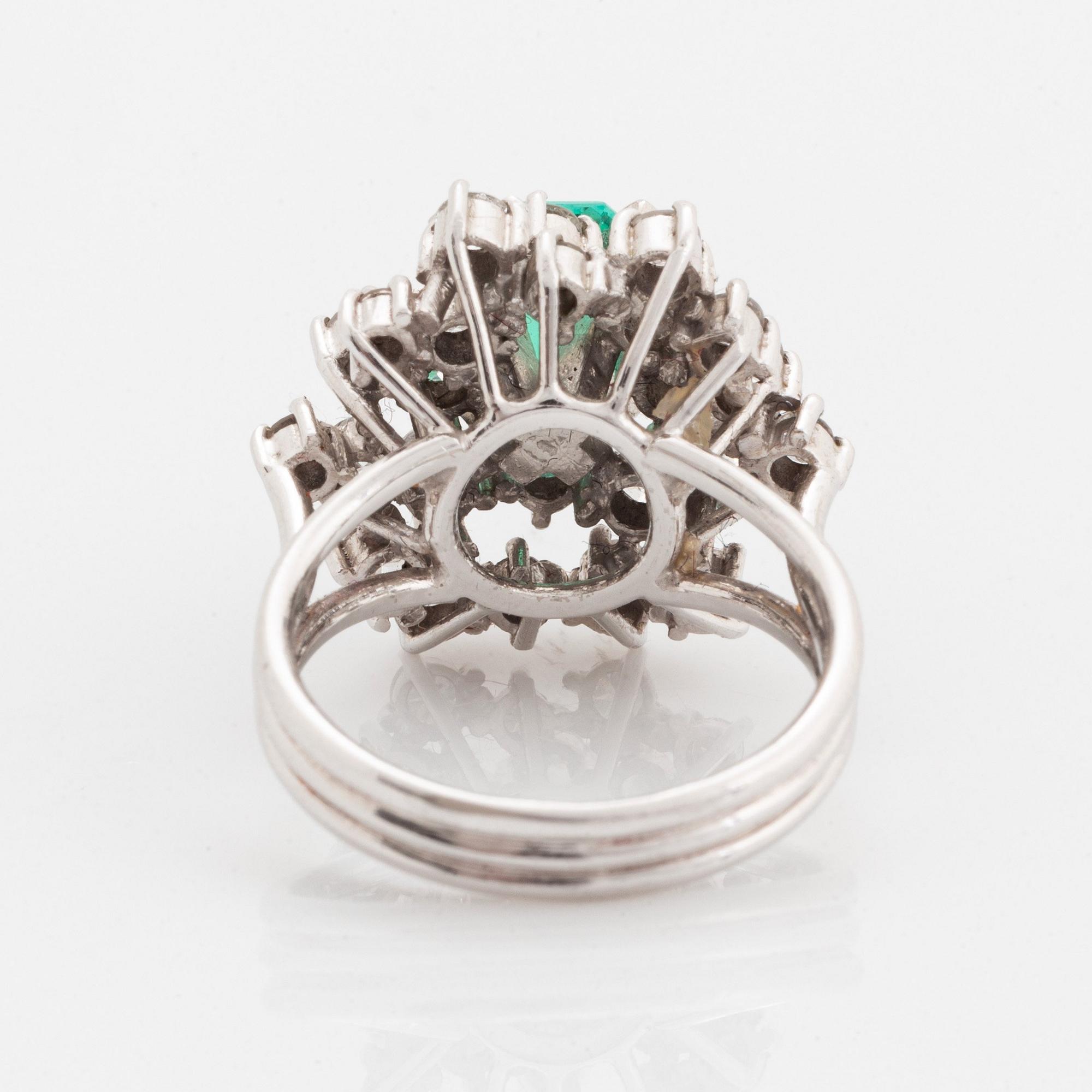 Ring platina med en fasettslipad smaragd och runda briljantslipade diamanter.