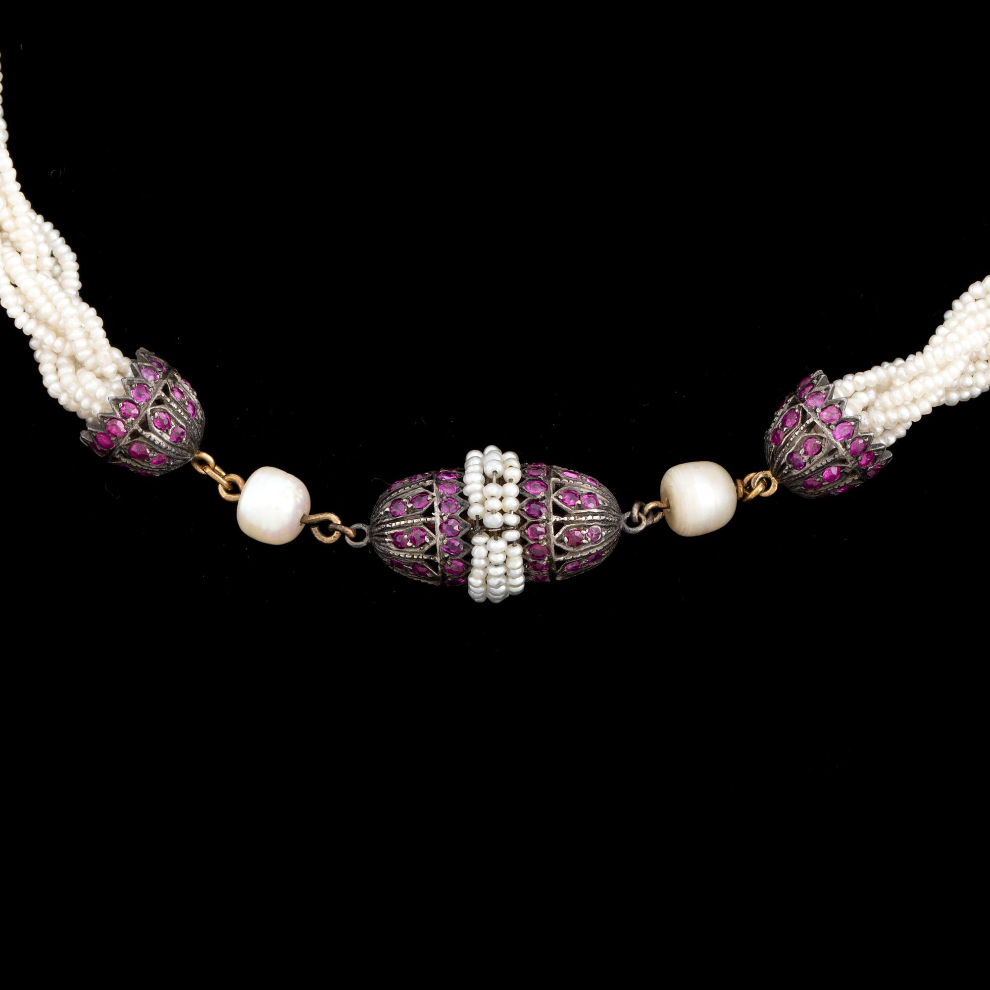 A necklace of cultured pearls and seed pearls with a silver clasp decorated with probably synthetic rubies.
