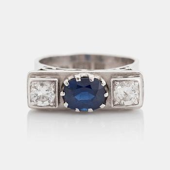 455. An 18K white gold ring set with a faceted sapphire, possibly synthetic, and round brilliant-cut diamonds.