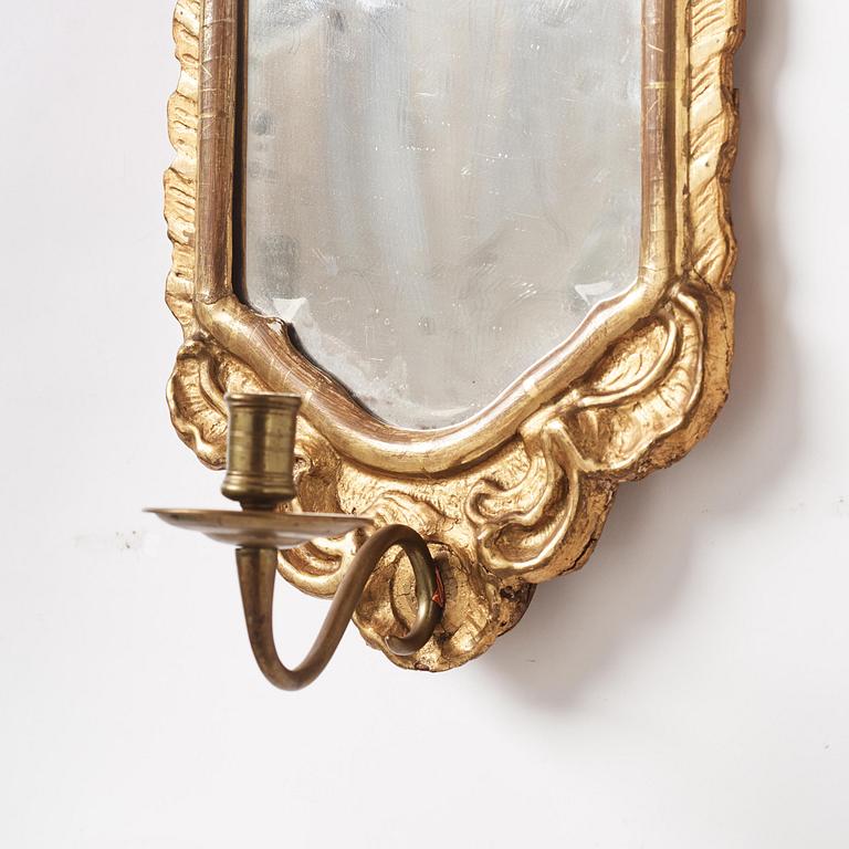 A pair of presumably German rococo giltwood one-branch mirrored wall-sconces, mid 18th century.