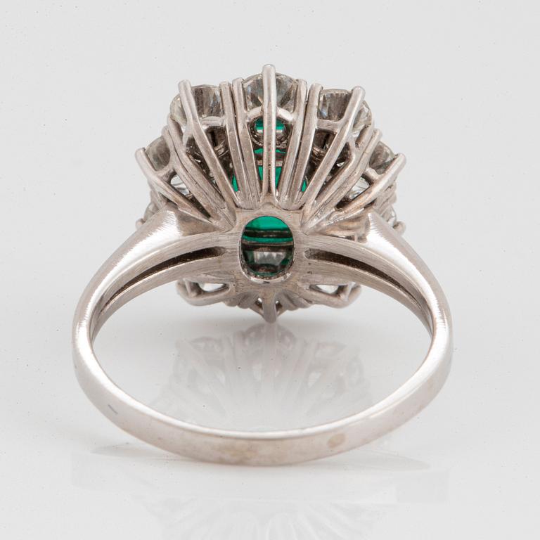 An 18K white gold ring set with a faceted emerald ca 1.15 cts and round brilliant-cut diamonds.