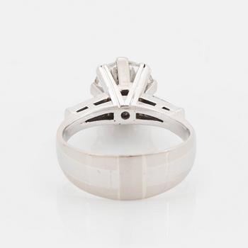 An 18K white gold ring set with a round brilliant-cut diamond and two tapered baguette-cut diamonds.