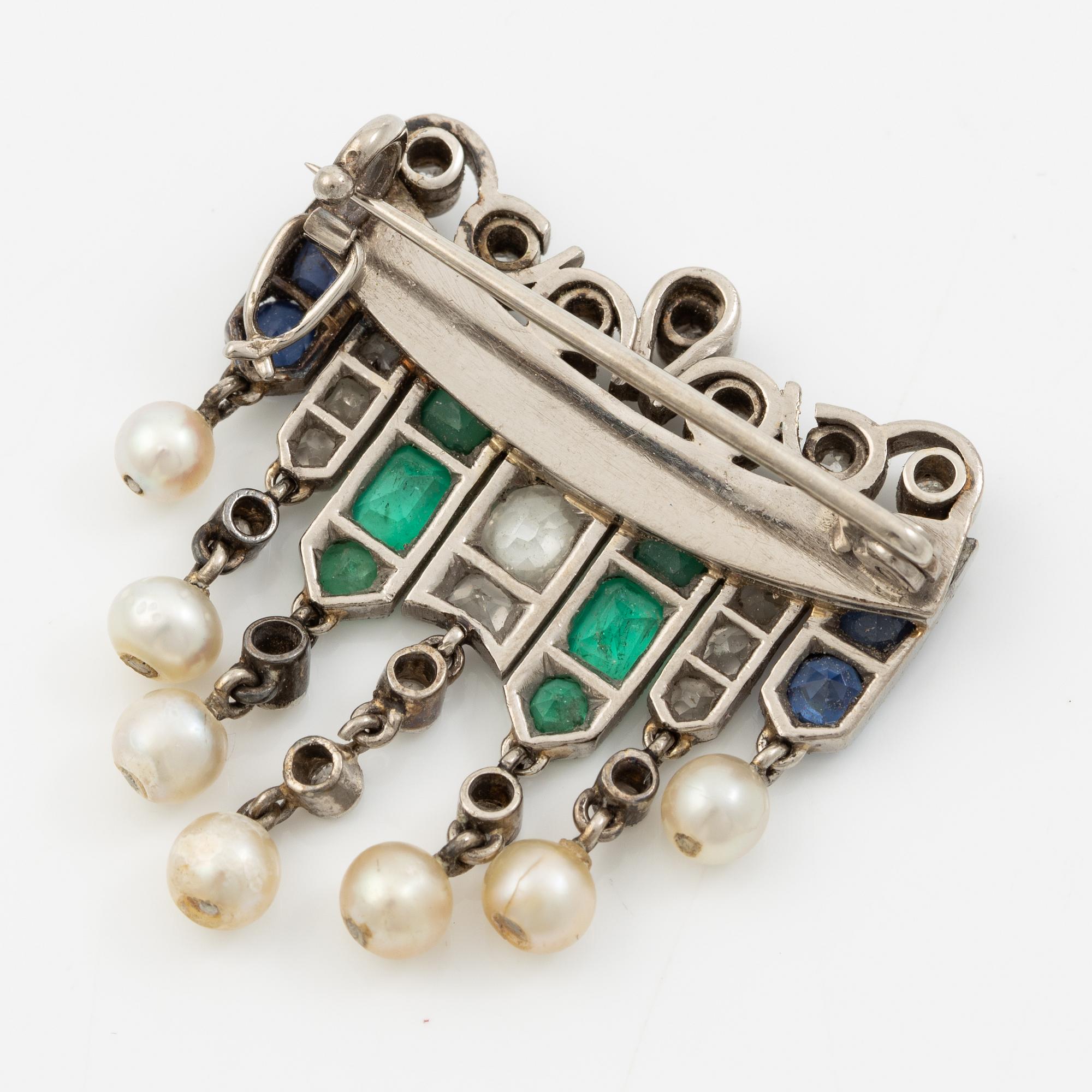 Brooch in platinum set with old-cut diamonds, sapphires, emeralds, and pearls.