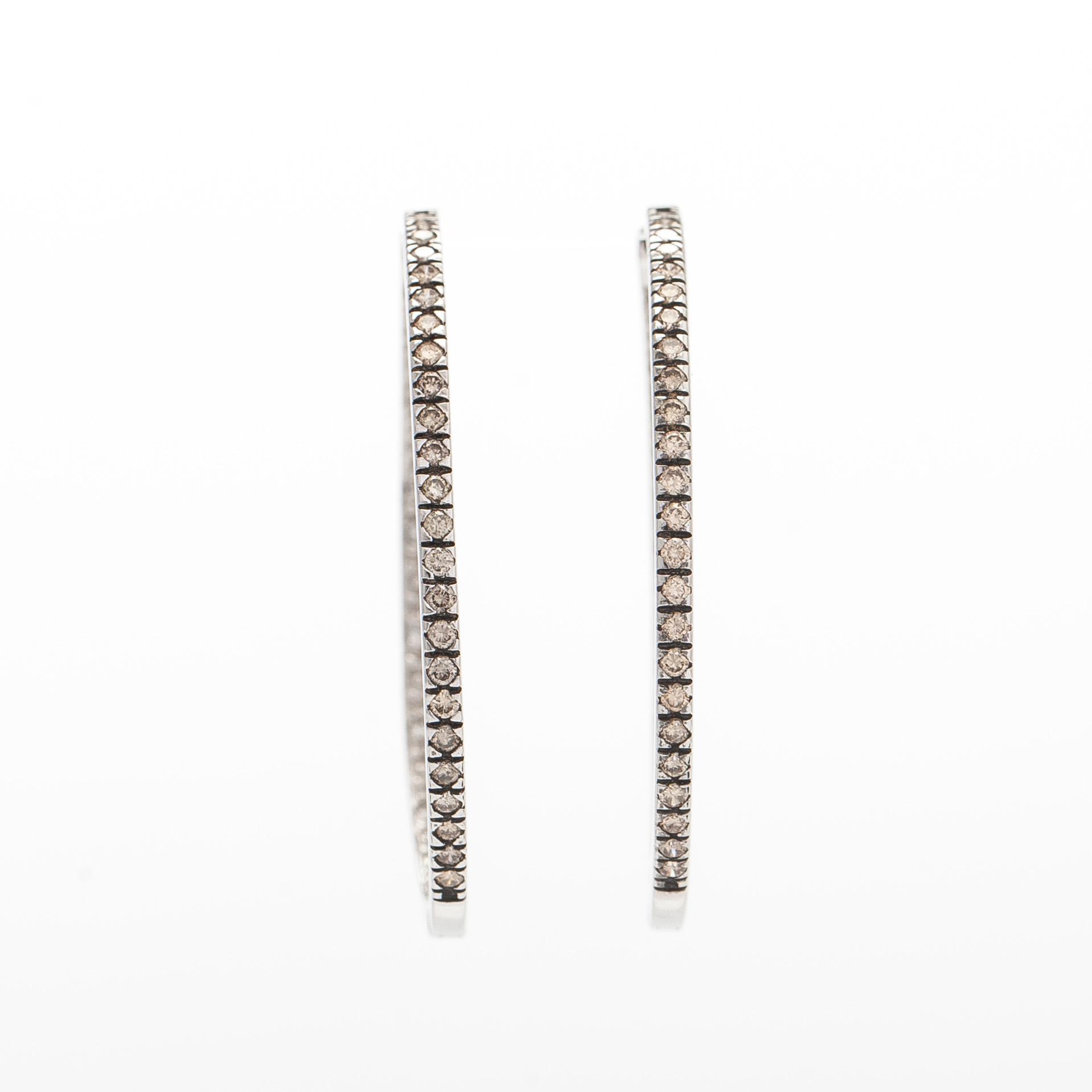 A pair of 14K white gold  hoop earrings with diamonds.