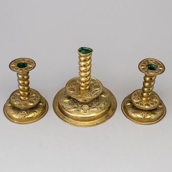 Three baroque style brass candle sticks.