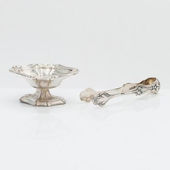 A silver sugar tong by Johan Warjus, and a silver salt cellar by Adolf Sper, St Petersburg 1856 and 1849.