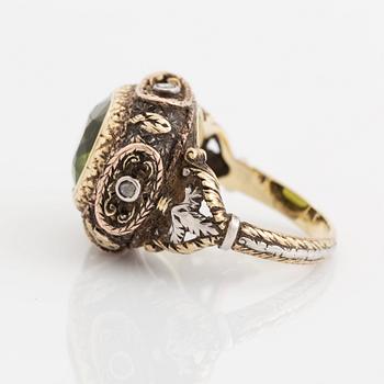 A silver and gold ring set with a faceted peridot and rose-cut diamonds.