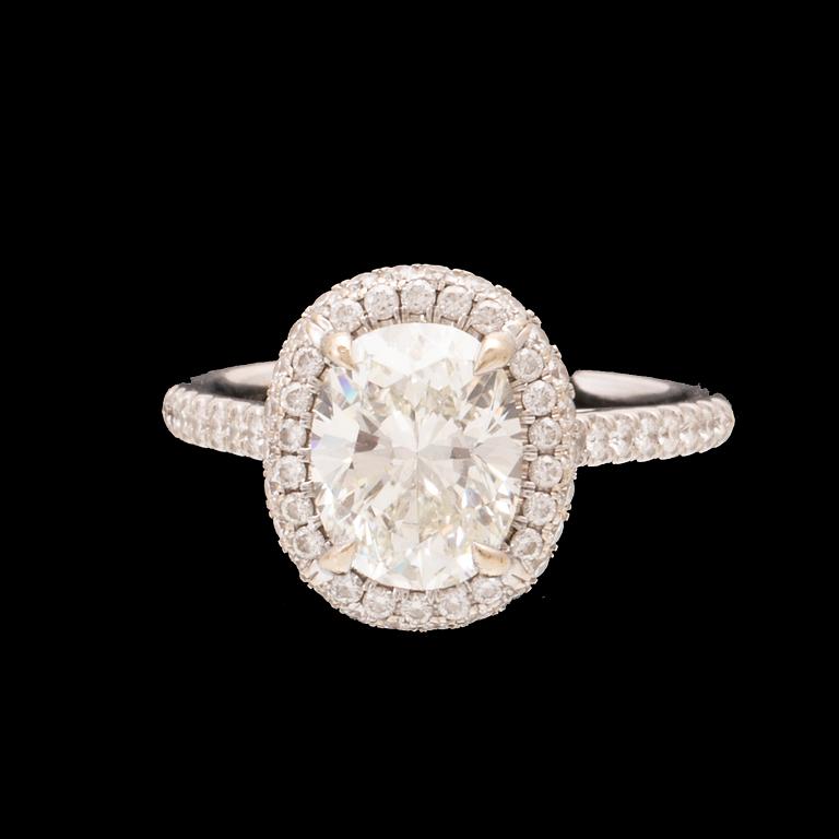 An 18K white gold ring by James Allen, set with an oval brilliant cut diamond in a halo of round brilliant cut diamonds.
