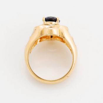 An 18K gold Junod ring set with a facted sapphire and tapered baguette-cut diamonds.