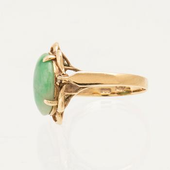 Ring in 14K gold with a green oval cabochon-cut stone and round brilliant-cut diamonds.