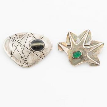 Två broscher, silver och stenar.