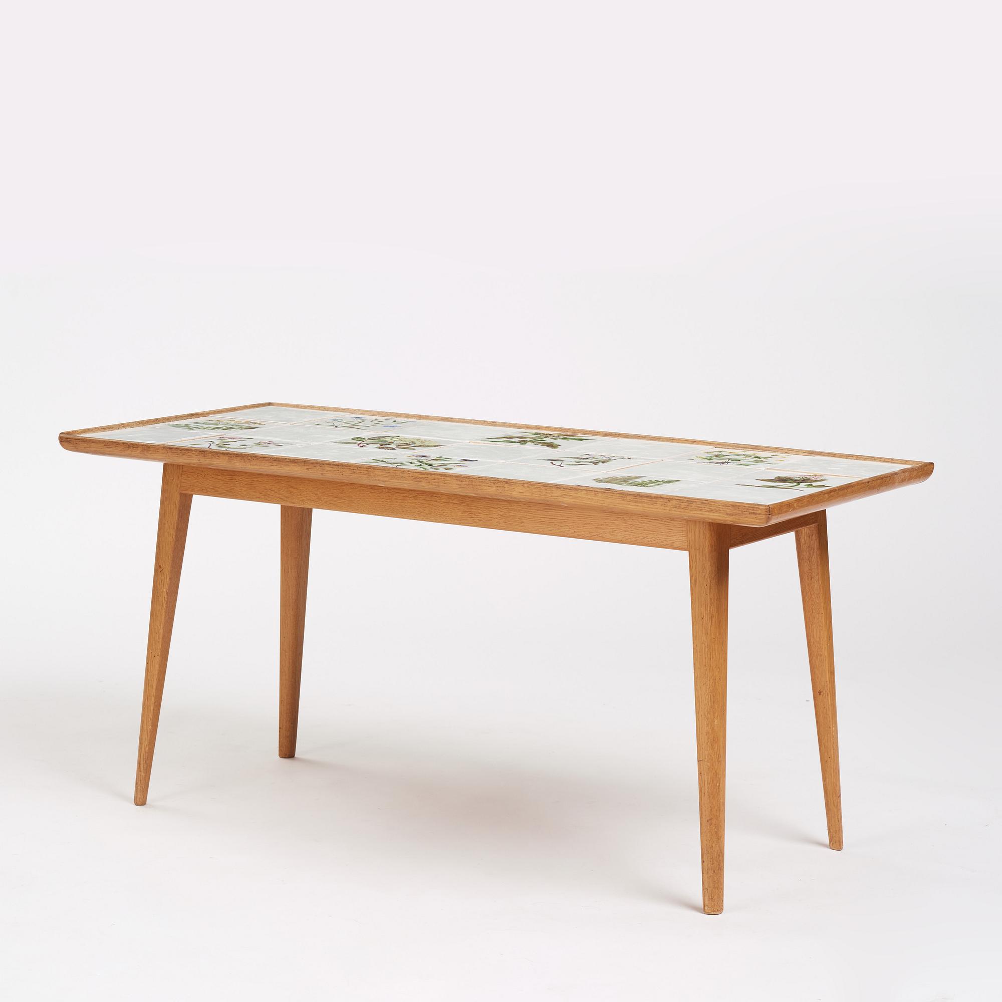 a Swedish Modern coffee table, decorated with Jobs' ceramic tiles, signed and dated 1941.