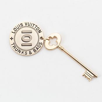 Louis Vuitton, a gold metal key magnet.