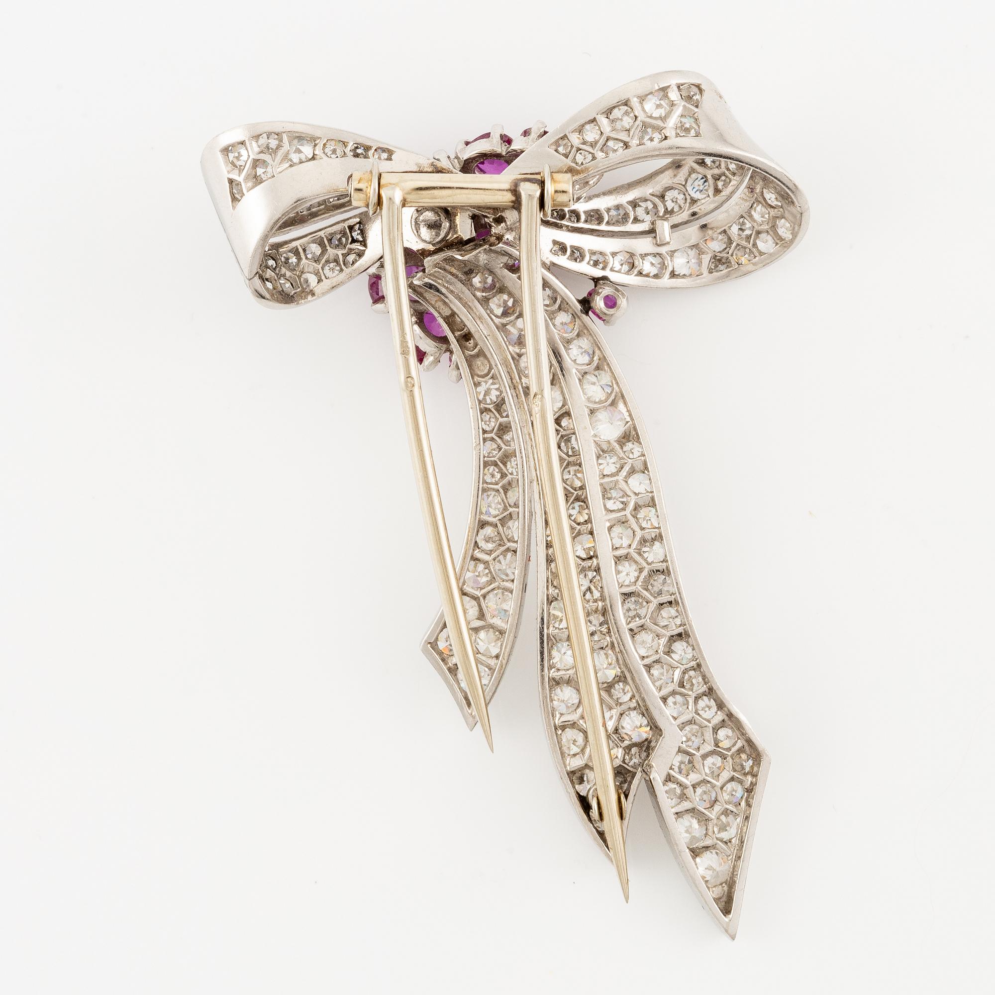 A brooch in platinum in the form of a bow with rubies and diamonds, likely from the 1950s.