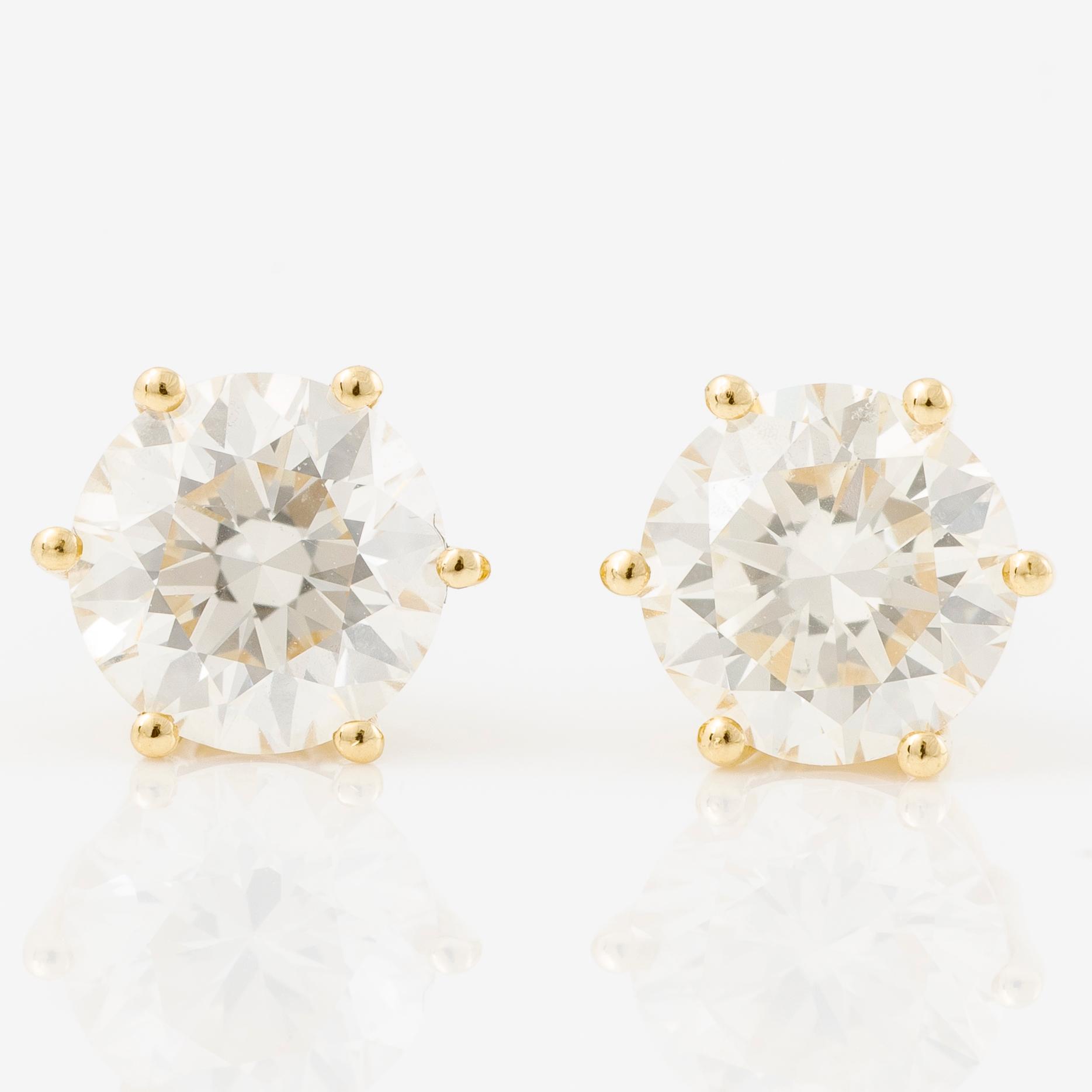 A pair of earrings in 18K gold set with two round brilliant-cut diamonds.