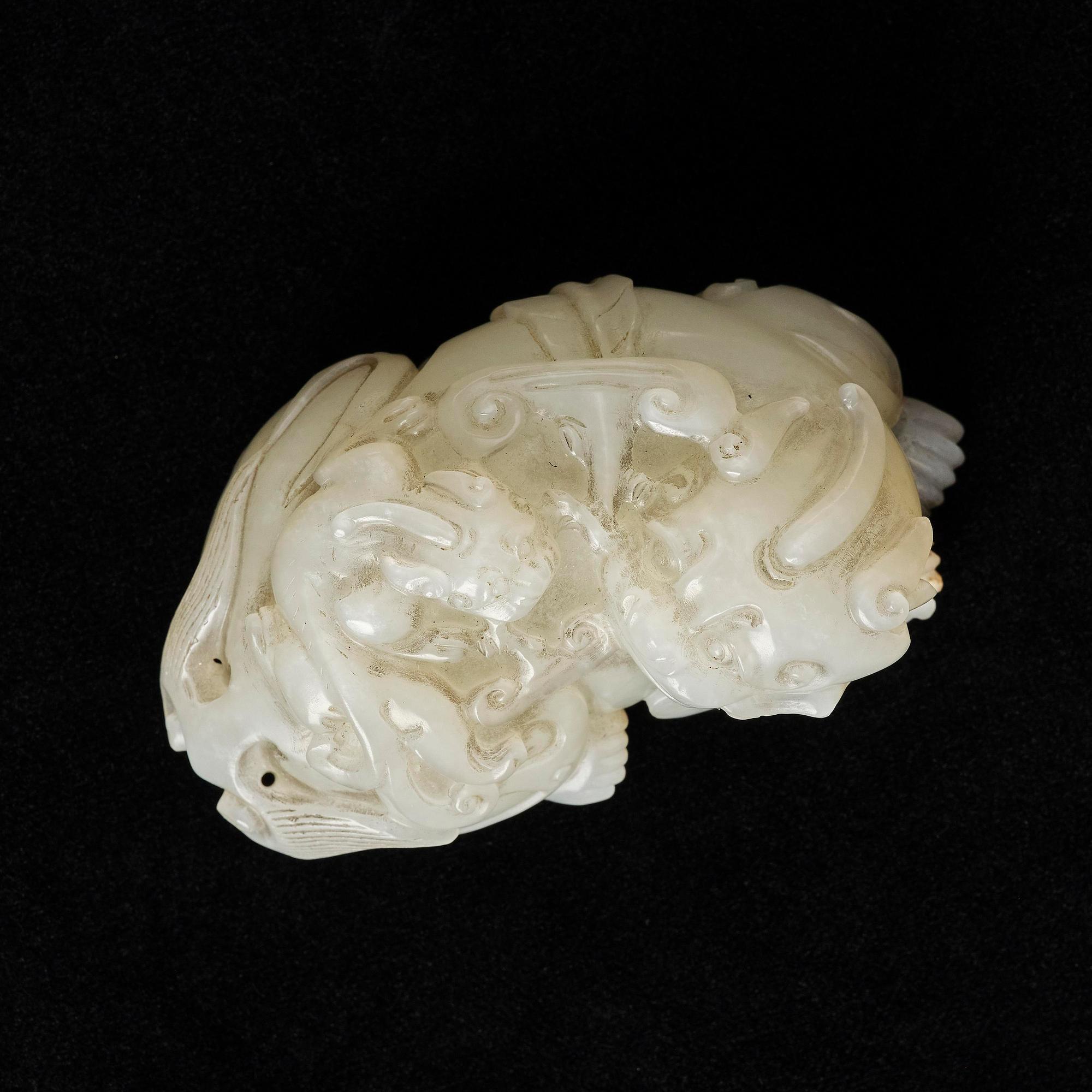 A Chinese nephrite carving of a recumbant lion with her cub, Qing dynasty.
