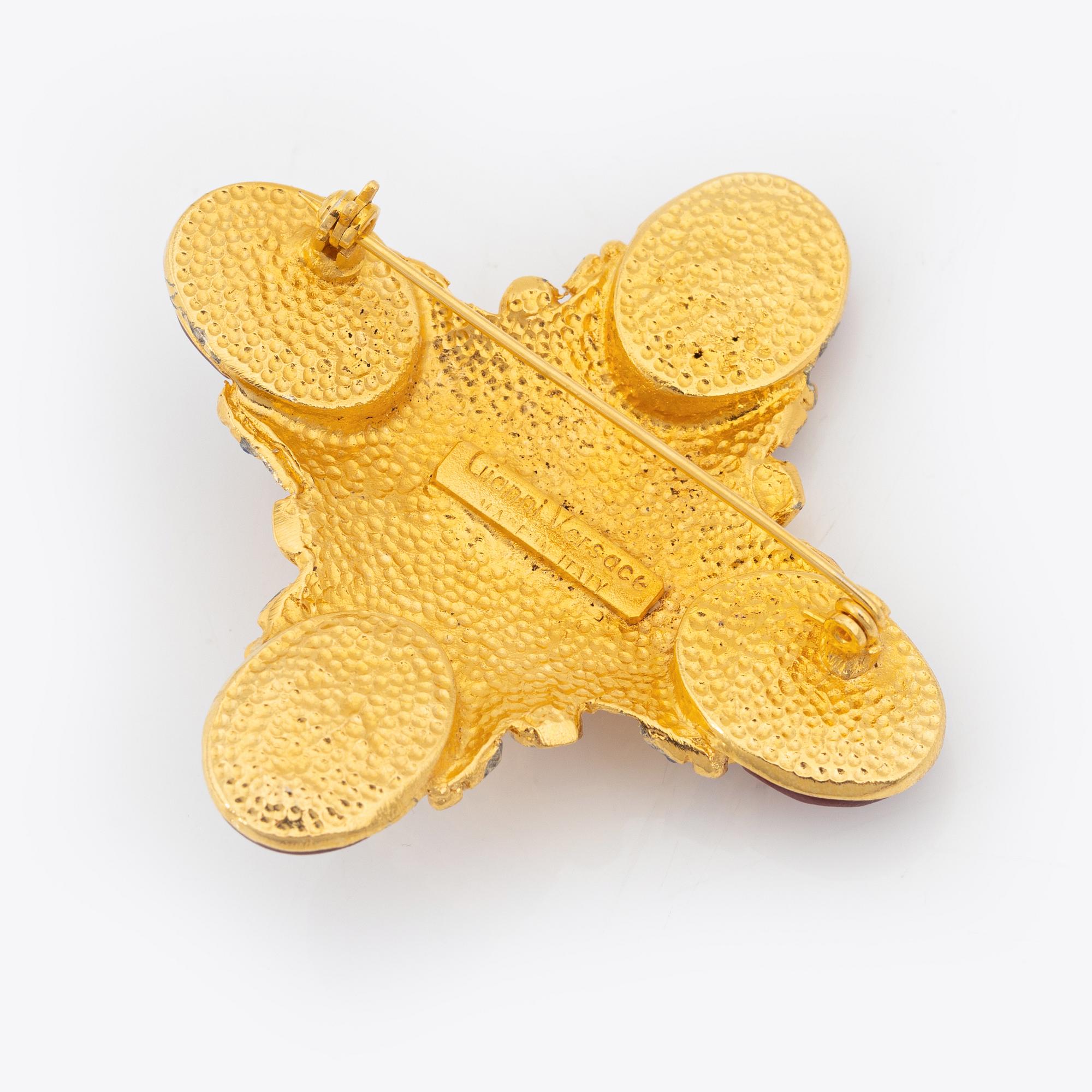 Gianni Versace, a gold tone and glass stone brooch.