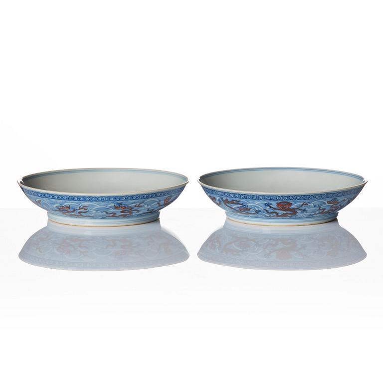 A pair of blue and white and iron red decorated dragon dishes, Qing dynasty with Qianlong mark.