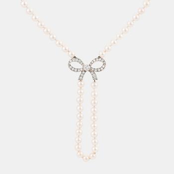 A cultured pearl necklace with a 14K white gold bow pendant set with round brillliant-cut diamonds.