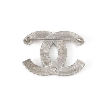 A white metal brooch by Chanel.