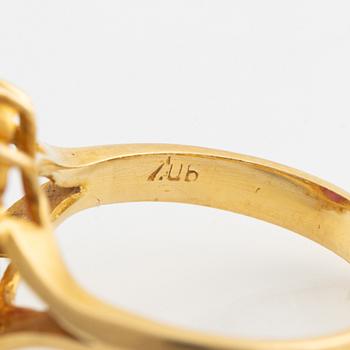 An 18K gold ring set with a cabochon-cut ruby and round brilliant-cut diamonds.