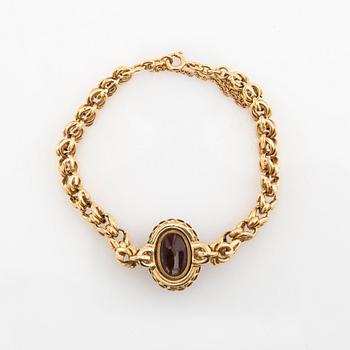 Bracelet in 18K gold set with rose-cut diamonds and an oval cabochon-cut garnet.