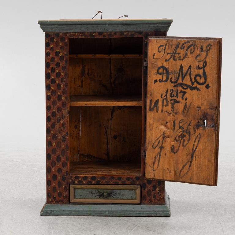 A painted wall cabinet, dated 1817.