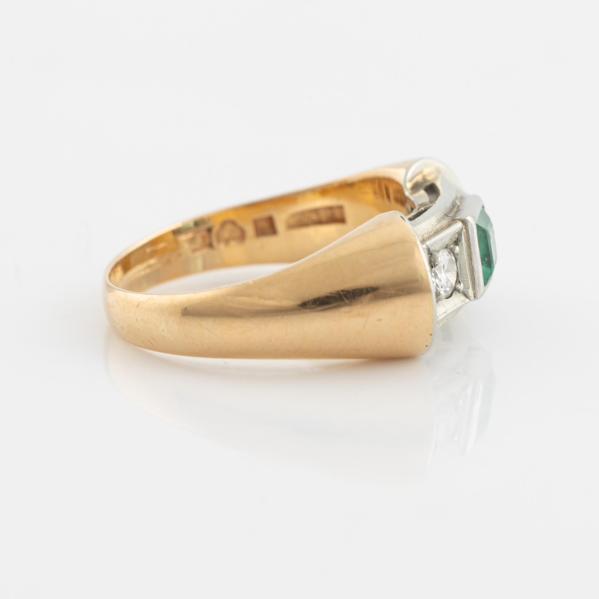 An 18K gold ring set with a step-cut emerald and round brilliant-cut diamonds.