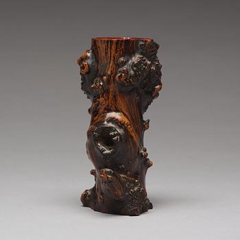 A Chinese wooden brush pot in the shape of a tree trunk.