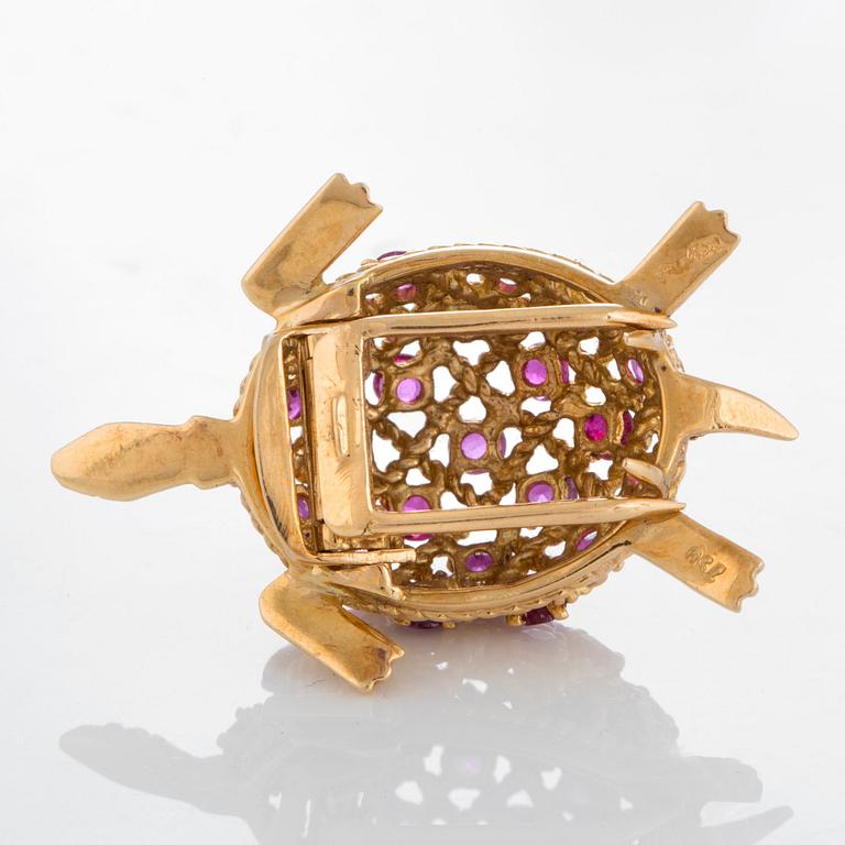 A Cartier turtle brooch in 18K gold set with rubies.