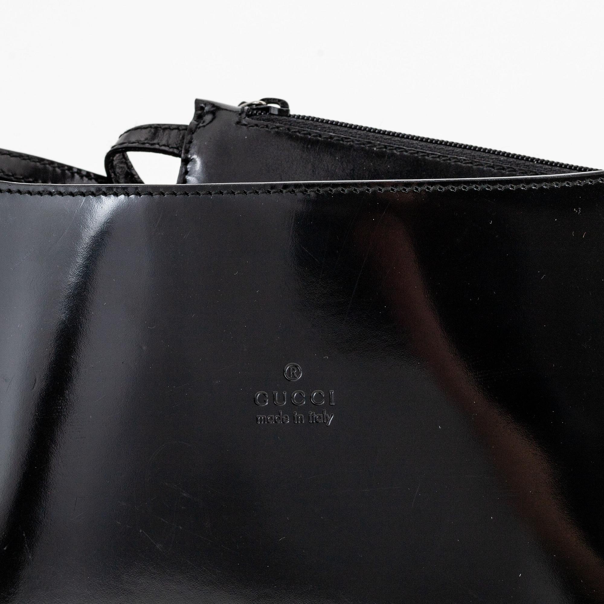 Gucci, a black, patent leather handbag.