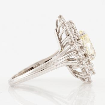 A platinum ring set with a pear-shaped yellow diamond and round brilliant-cut diamonds.