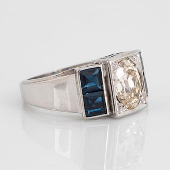 An 18K white gold ring set with an old-cut dimond weight ca 1.50 cts and step-cut sapphires.