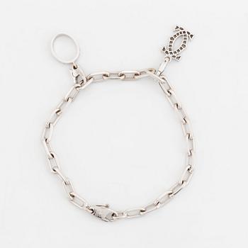 An 18K white gold Cartier "Spartacus" bracelet with two charms.