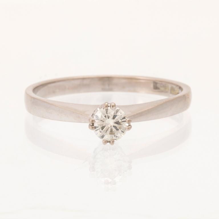 An 18K white gold solitaire ring set with a round brilliant-cut diamond.