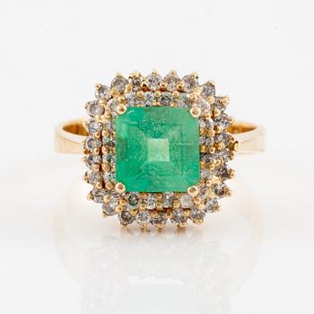 Ring in 18K gold set with a faceted emerald and round brilliant-cut diamonds.