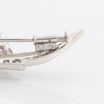 An 18K white gold brooch set with round brilliant-cut diamonds.