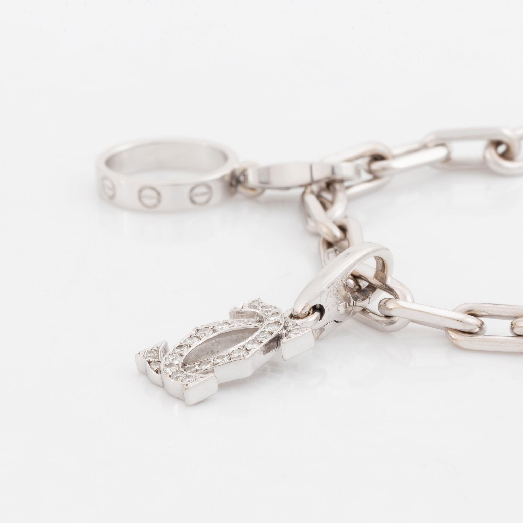 An 18K white gold Cartier "Spartacus" bracelet with two charms.