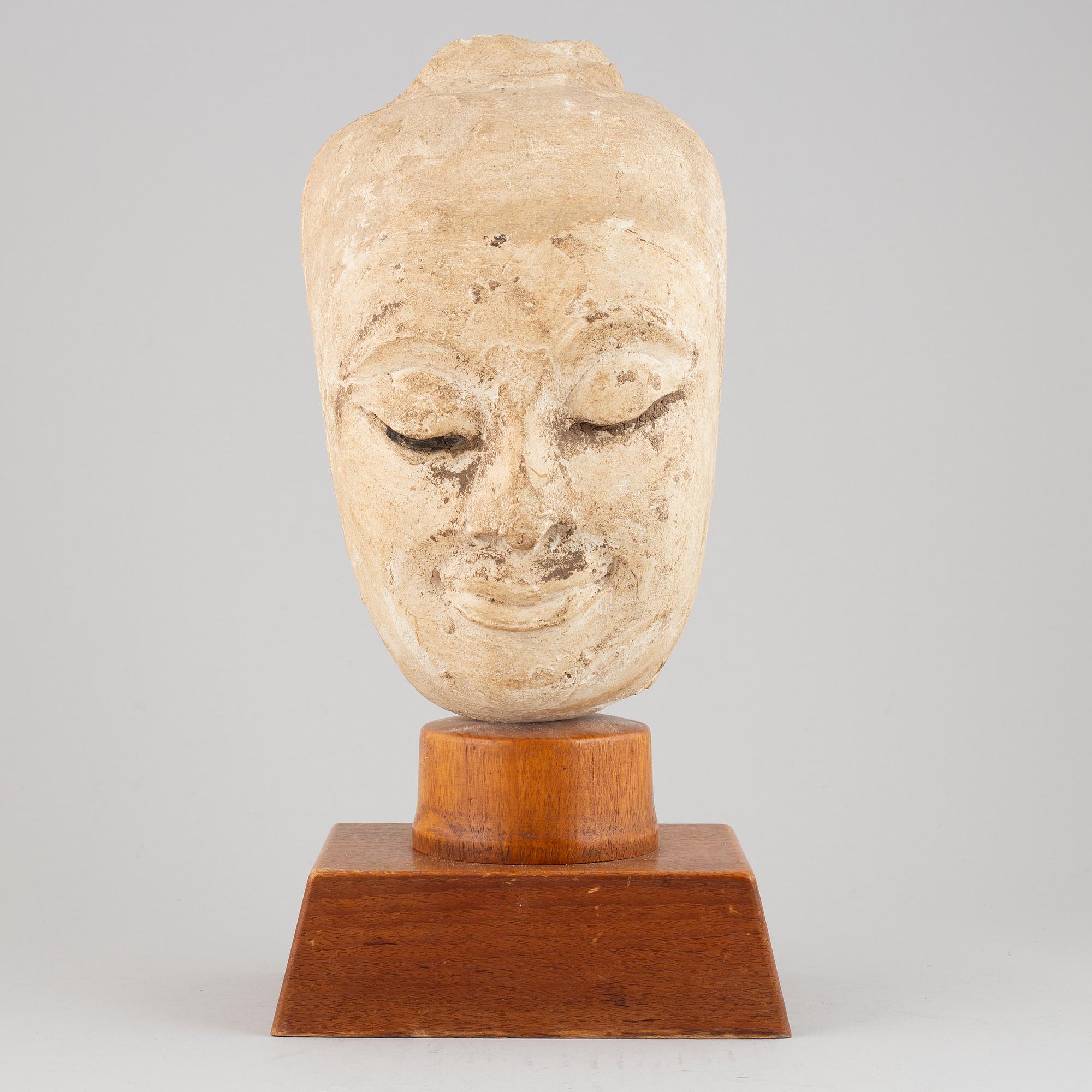 A South East Asian stone mass sculpture of a head, presumably modern manufacturing.
