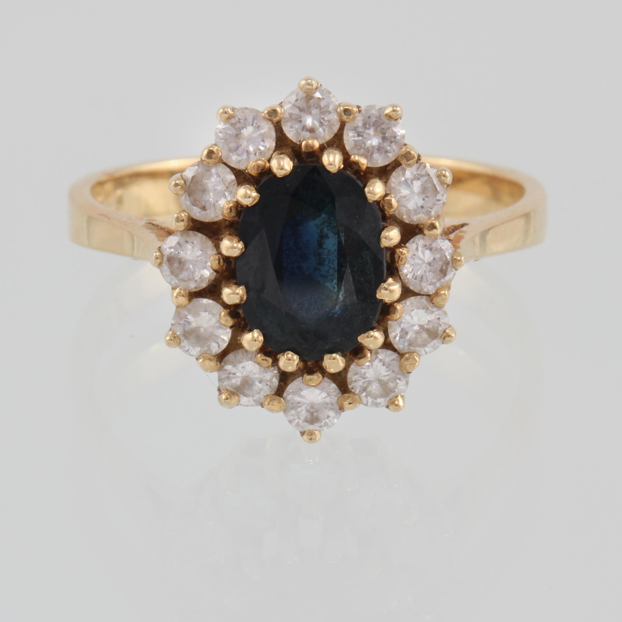 RING, 18K guld med ovalslipad blå safir samt 12 briljantslipade diamanter 0.73 ct, kattfotstämplad. Vikt 5,3 gram.