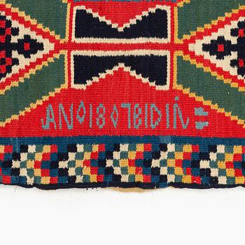 A carrige cushion, 'Träd och timglas', double-interlocked tapestry, c. 102 x 53 cm, signed BID IÅ, dated 1807.