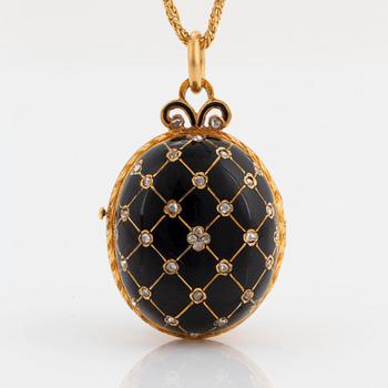 An egg shaped locket in 18K gold and black enamel set with rose-cut diamonds and rubies.