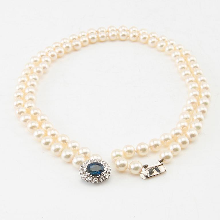 Necklace of cultured pearls with an 18K white gold clasp featuring an oval faceted sapphire and round brilliant-cut diamonds.