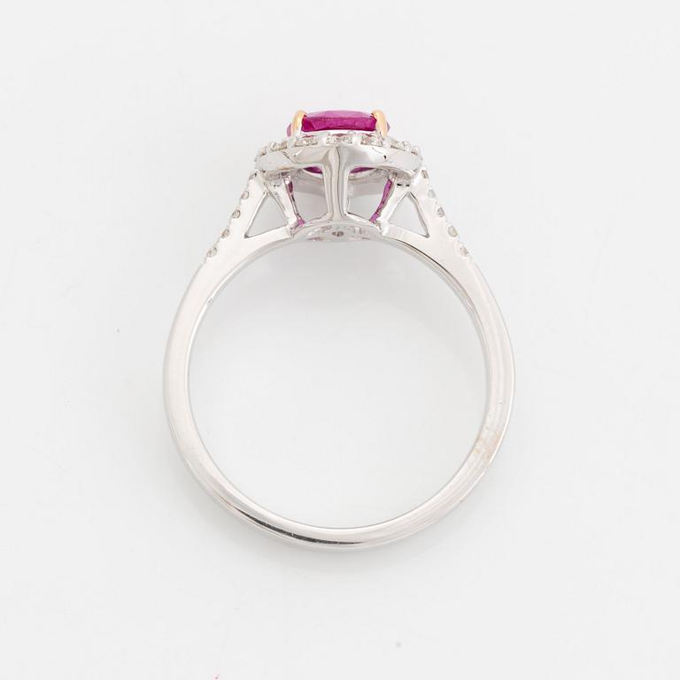 An 18K white gold ring set with a faceted pink sapphire and round brilliant-cut diamonds.