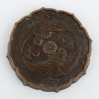 A bronze mirrorshaped paperweight, Japan 195. Decorated with Chrysantemum and birds.