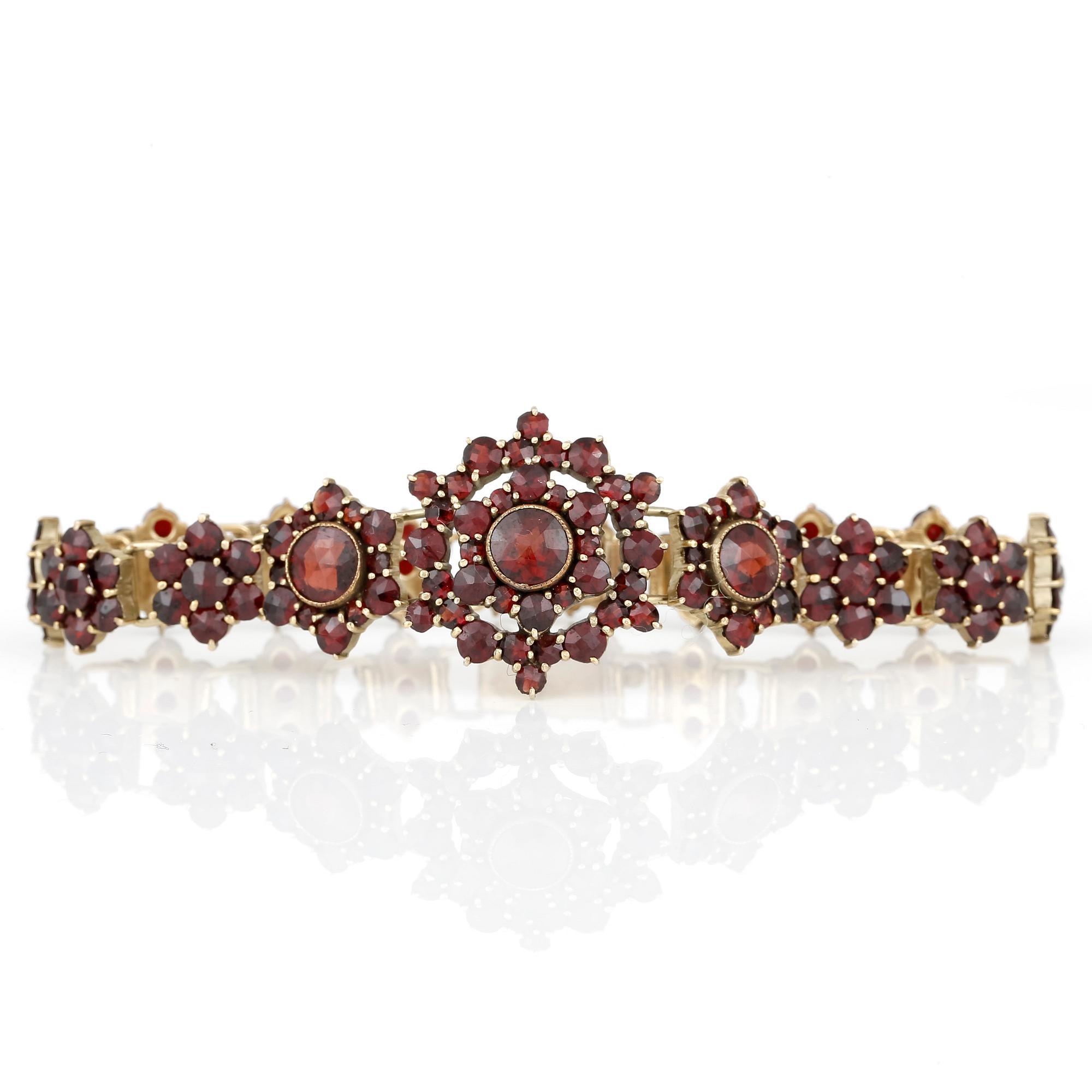 HALSBAND, ARMBAND, BROSCH samt ÖRHÄNGEN, ett par, med fasetterade granater, 1900-talets första kvartal.