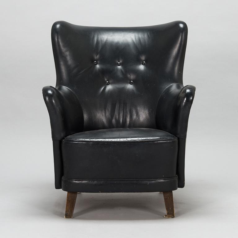 A 1950s black leather armchair.