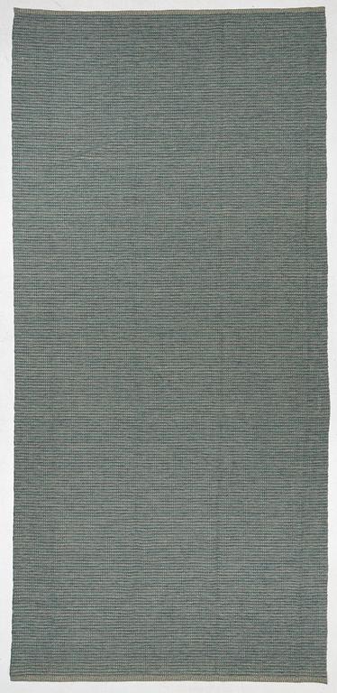 A "Dogtooth metallic green" carpet, Vandra rugs, c. 562 x 265 cm.