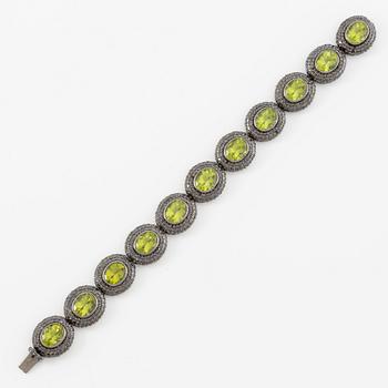 Bracelet in 18K gold with oval peridots and brilliant-cut black diamonds.