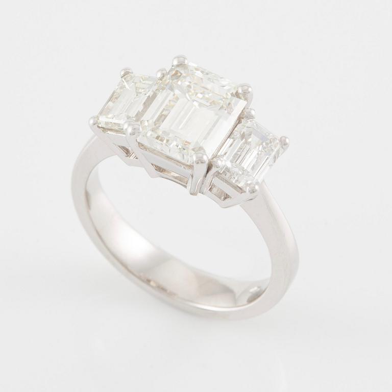 An 18K white gold ring set with three emerald-cut diamonds.